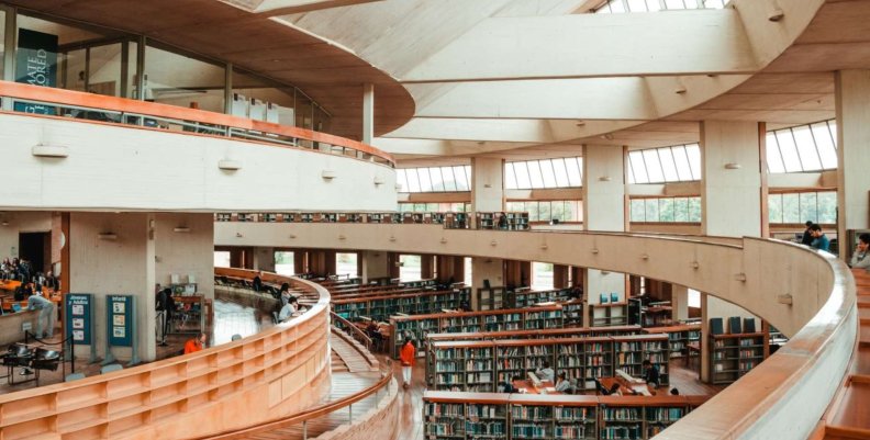 Pasillos con suelo de madera y paredes blancas: en medio, estantes de libros