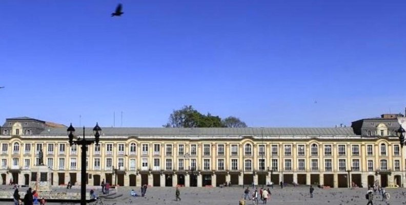 Edificio de color blanco con muchas ventanas. Arriba se ve el cielo azul