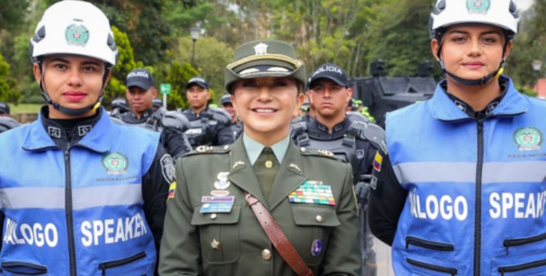 Fotografía tomada de la Policía Nacional. Mujer vestida de policía en el centro con dos mujeres con chalecos azules y cascos blancos a los lados
