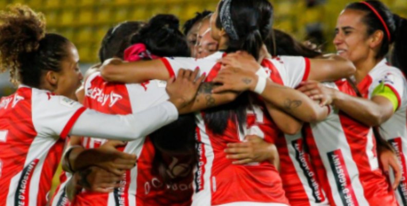 Jugadoras de fútbol de uniforme rojo abrazándose 