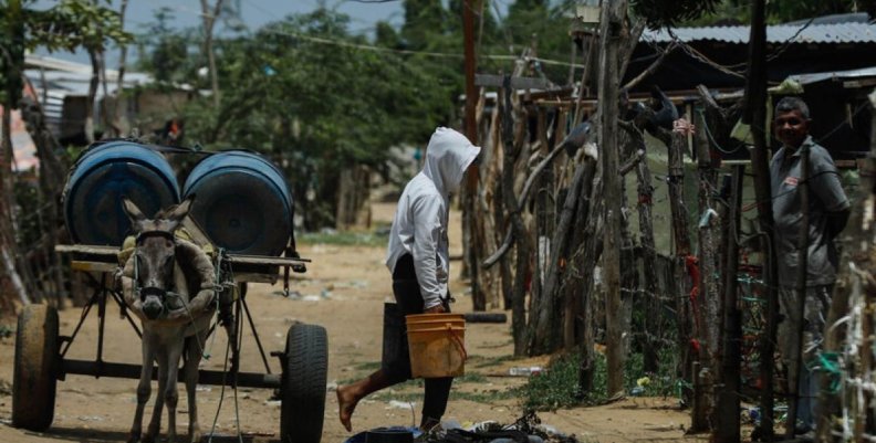 Un hombre cargando unos bidones de agua