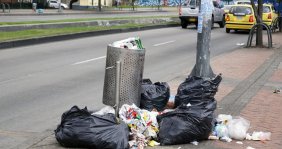 Cesto de basura lleno con basura alrededor