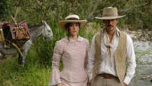 Un hombre y una mujer, vestidos con ropa blanca antigua. Atrás hay un caballo