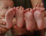Pies de dos bebés al lado de sus padres