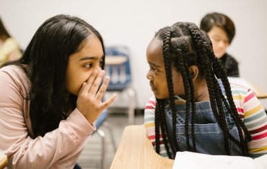 Dos niñas hablando en un salón de clases