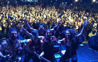 Una banda posando detrás de un público lleno de personas