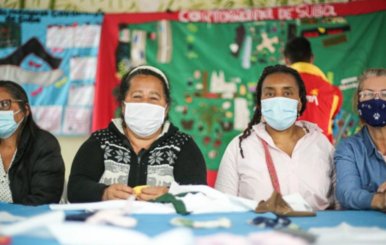 Cuatro mujeres mayores sentadas en una mesa de tejido