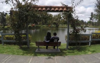Un hombre y una mujer sentados frente al lago del Parque de los Novios 